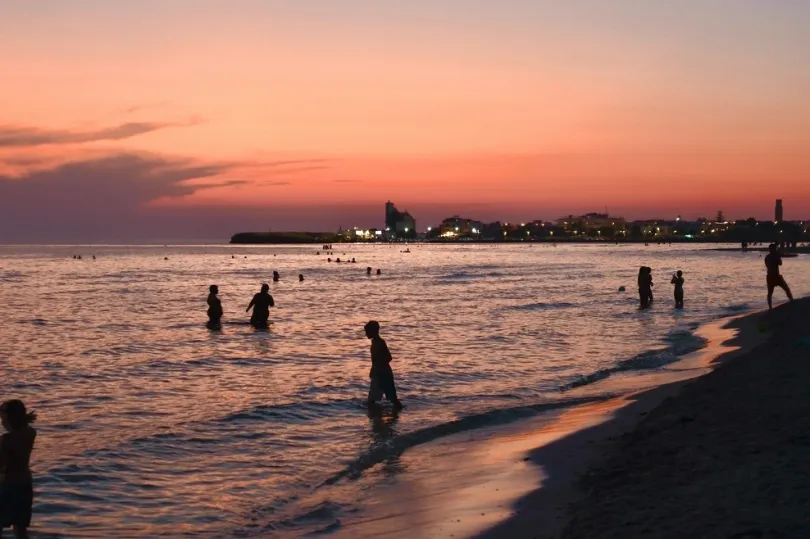 Menschen am Strand beim Sonnenuntergang.