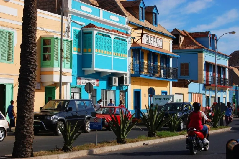 Straße von Mindelo, gefüllt mit Menschen, Autos und scooters.