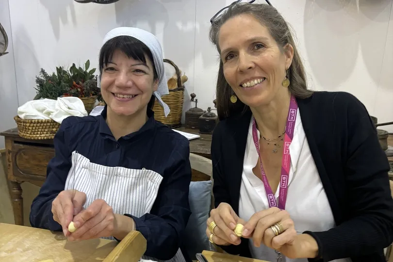 zwei Frauen, die in der Küche am Tisch Gnocchi formen.