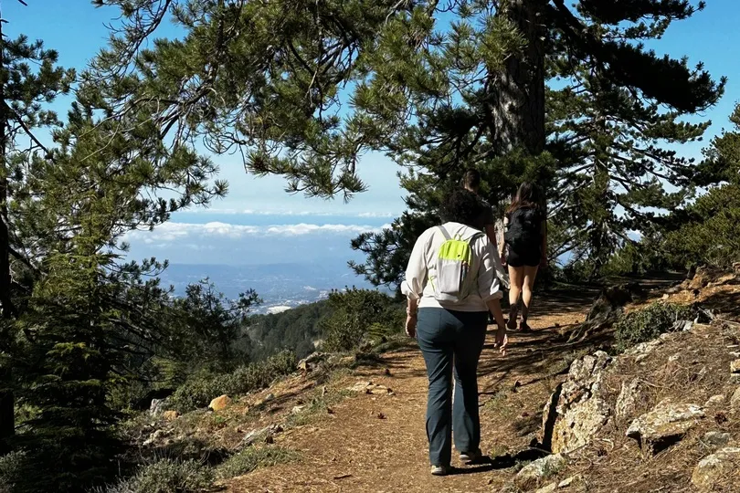 Frau wandert durch Hügel mit Aussicht aufs Meer.