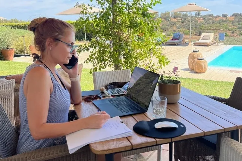 Eine Frau, die draußen mit ihrem Laptop telefoniert.