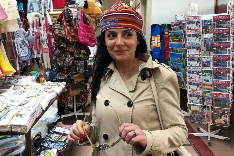 A woman standing in a shop holding her sunglasses.