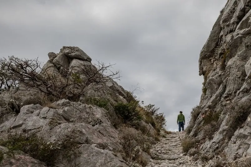 A person standing within rocks of a mountain.
