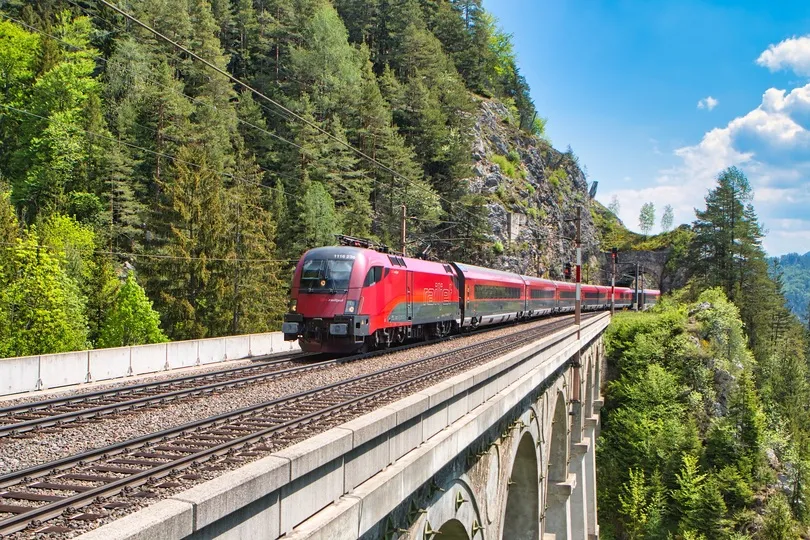 Ein ÖBB Railjet-Zug auf einer Zugbrücke in den Bergen von Österreich.