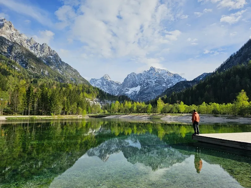 Ein Mann steht am Ufer eines Bergsees im Triglav Nationalpark