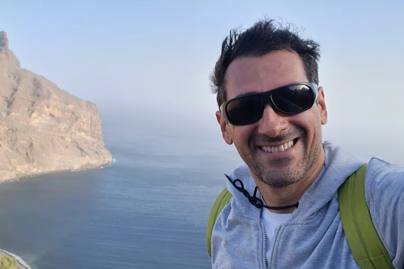 Man met zonnebril maakt een foto voor de zee. 