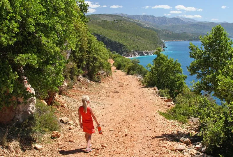 Mädchen läuft in Albanien über einen Weg an der Küste. 