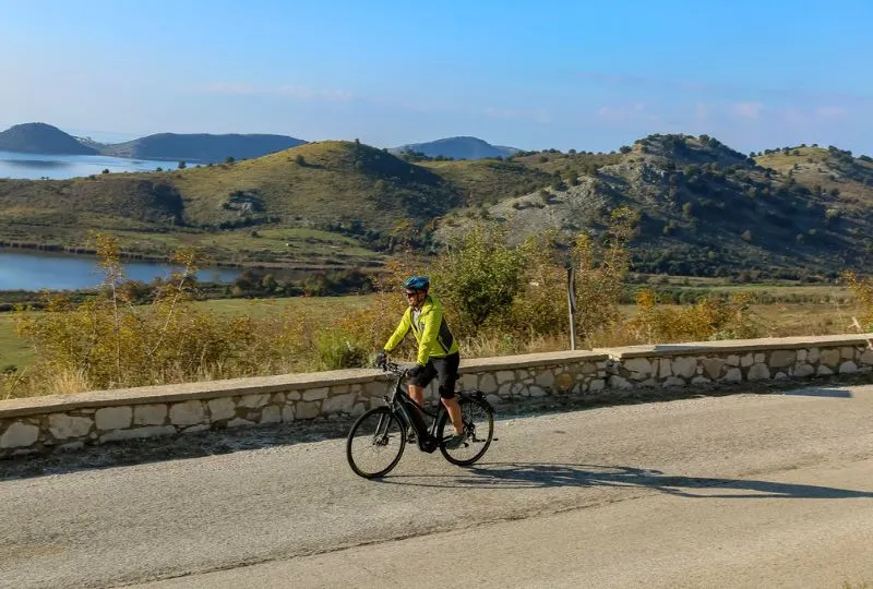 Fahrradfahrer fährt durch eine hügelige Landschaft Albaniens.