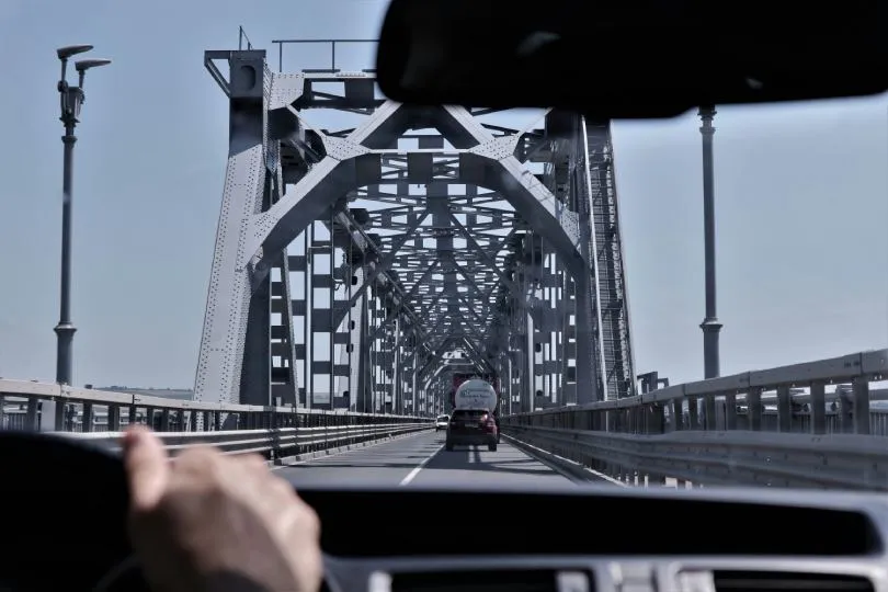 Blick aus dem Auto auf eine Fahrt über eine Stahlbrücke in Bulgarien mit vorausfahrendem Lkw.