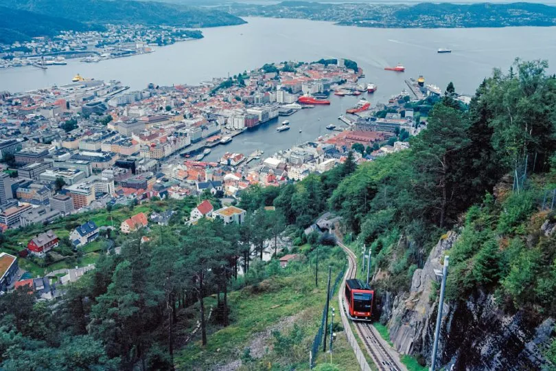 Standseilbahn fährt einen steilen Hang hinauf, im Hintergrund Hafenstadt mit Bucht, Schiffen und dicht bebauten Vierteln.