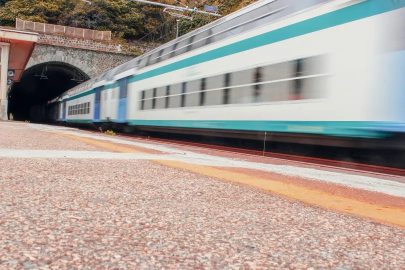 Schnell fahrender Zug verlässt einen Tunnel, aufgenommen aus niedriger Perspektive mit Bewegungsunschärfe.