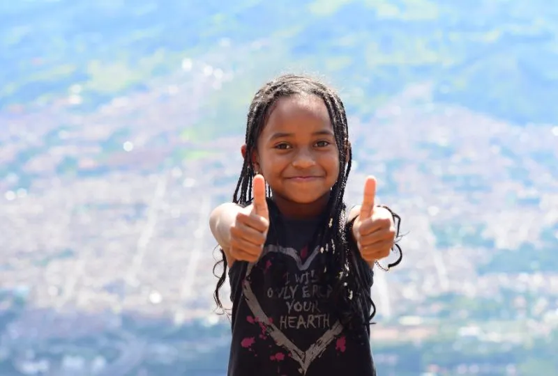 Kolumbianisches Mädchen gibt zwei Daumen hoch.