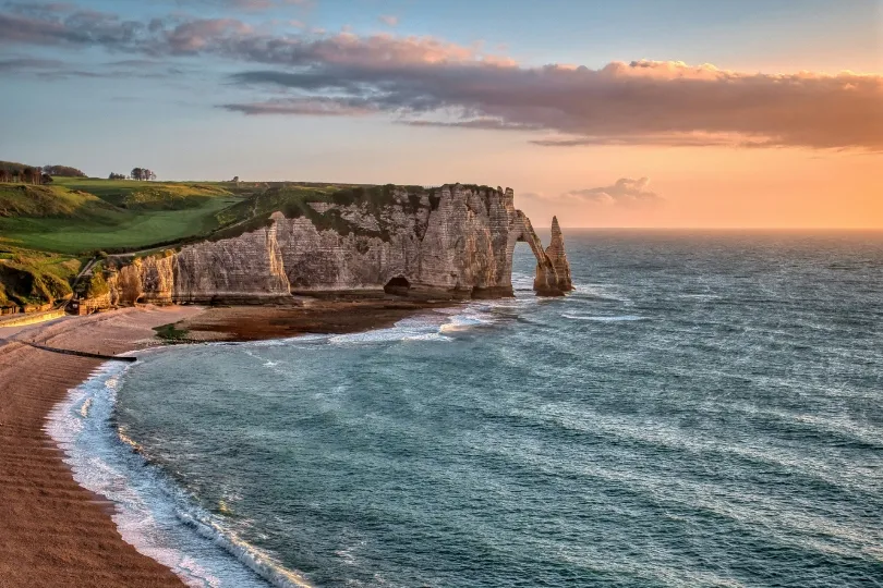 Kreidefelsen und Felsbogen von Étretat in der Normandie bei Sonnenuntergang mit Blick auf das Meer und die Küste.