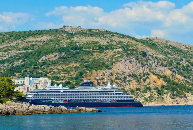 Riesen Kreuzfahrtschiff an einem kleinen Hafen in einer Stadt direkt in den Bergen.