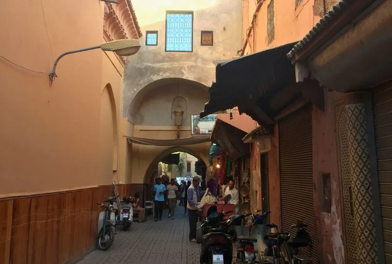 Einheimische und Mofas in einer Seitengasse einer Medina in Marokko in den Abendstunden.