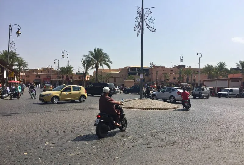 Mofafahrer, Taxis und andere Verkehrsteilnehmer fahren auf einem Platz in einer marokkanischen Stadt.
