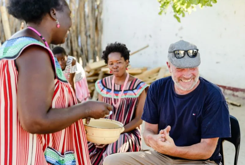 Reisender und Gastfamilie in Namibia lachen gemeinsam.