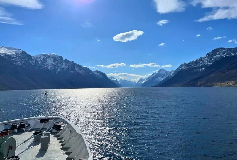 Aussicht auf den Fjord und die schneebedeckten Berge Norwegens vom Hurtigruten Schiff aus.