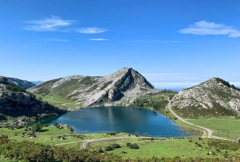 Straße führt an einem See inmitten der Gebirge der Picos de Europa in Spanien entlang.