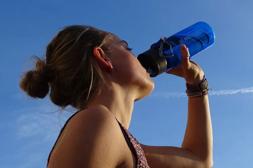 Woman drinking out of a Lifestraw filter bottle.