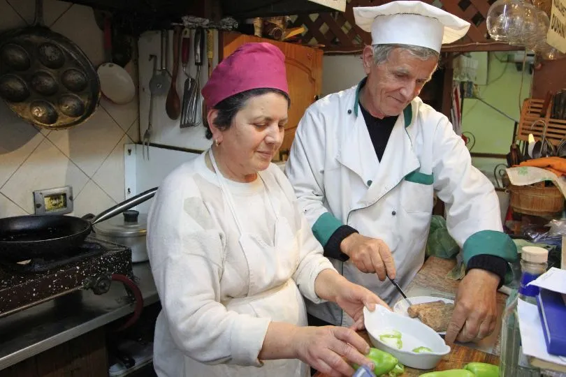 Dame und Herr mit Kochbegleitung bereiten gemeinsam eine Mahlzeit zu.