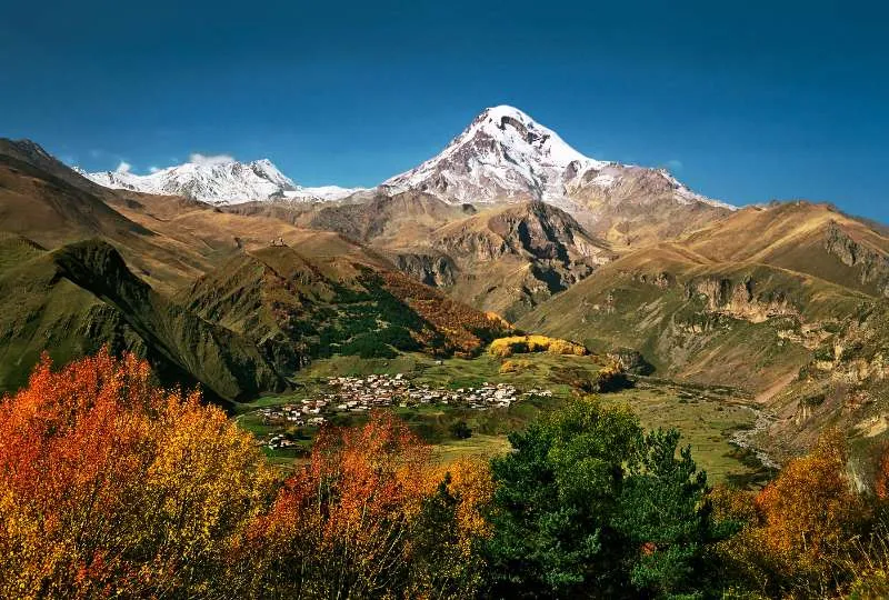 Der weiße Gipfel des Mount Kazbek, Georgien, türmt über der bunten Herbstlandschaft des Gebirges.