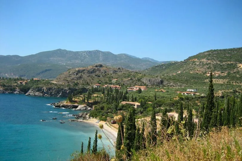 Küste bei Stoupa, Peloponnes, wo grüne Berge auf das türkise Meer treffen.
