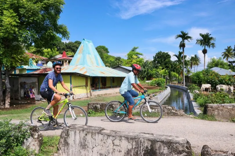 Tourist und Indonesier fahren gemeinsam mit dem Fahrrad durch die tropische Landschaft.