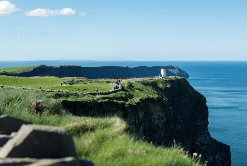 Die berühmten Cliffs of Moher in Irland mit ihren saftig-grünen Wiesen an einem sonnigen Tag.