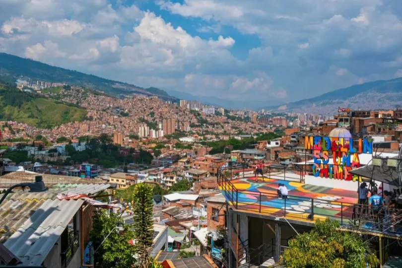 Die bunte Stadt Medellin mit ihren grünen Bäumen zwischen den rötlichen Dächern der Häuser.