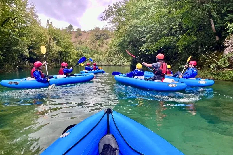Touristen in Kroatien paddeln in blauen Rafting Booten durch das türkise Wasser.