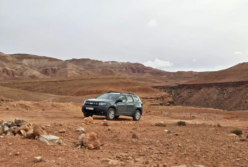 Mietwagen steht in der kargen, bergigen Landschaft Marokkos.