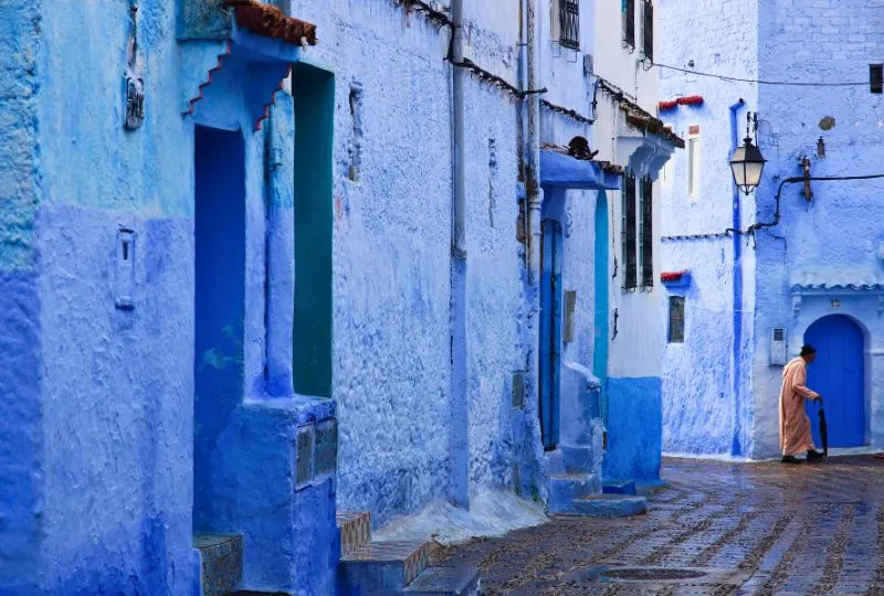 Mann spaziert durch die blauen Gassen Chefchaouens, einer kleinen blau angestrichenen Stadt in Marokko.