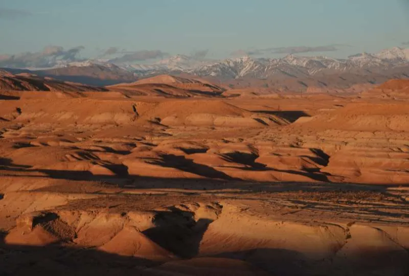 Wüstenhafte Landschaft in Marokko mit dem hohen Atlasgebirge im Hintergrund.
