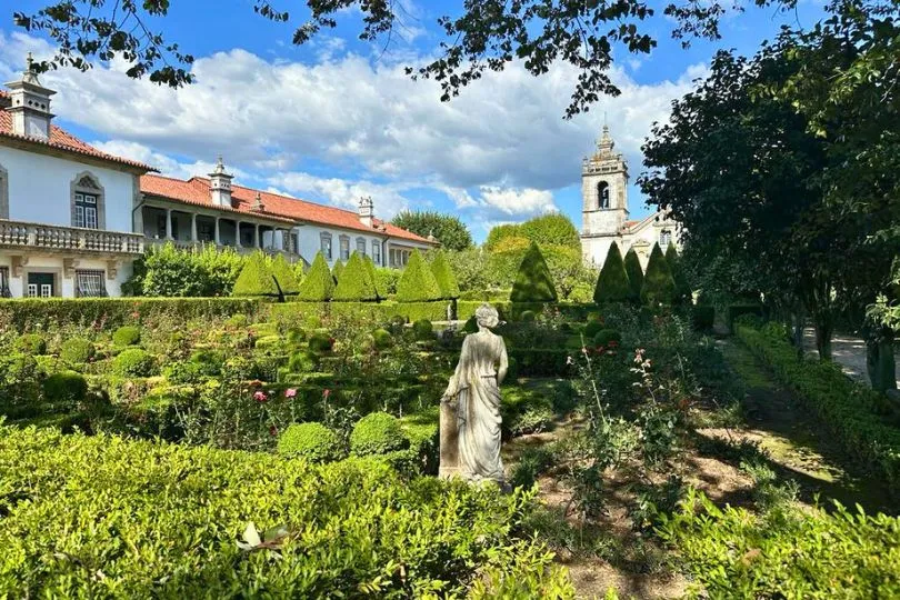 Grüner Klostergarten mit einer Frauenstatue in der Mitte, Portugal.