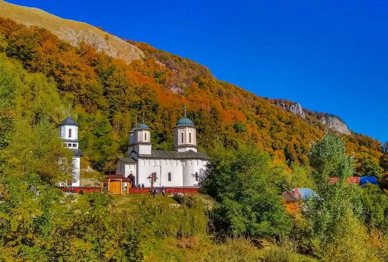 Weiße Kapelle steht inmitten eines Waldes mit Herbstfarben in Rumänien.