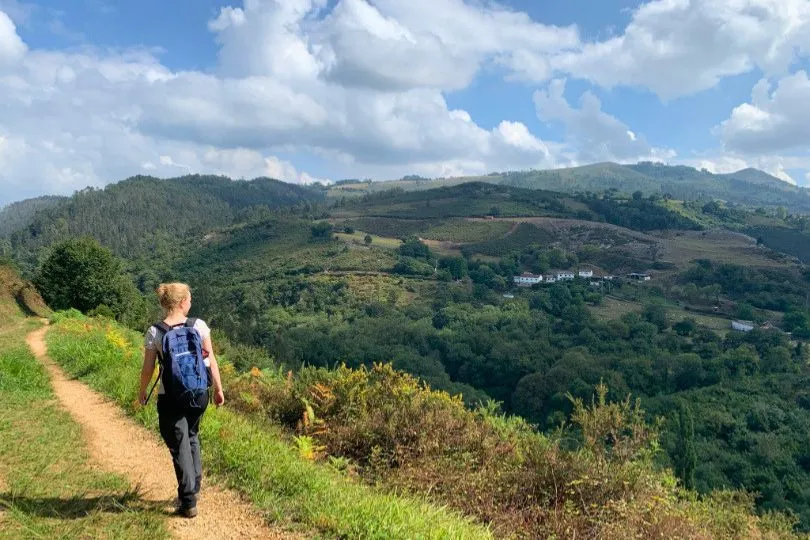 Frau auf einem Wanderpfad in den grünen Landschaften der Picos de Europa, Spanien.