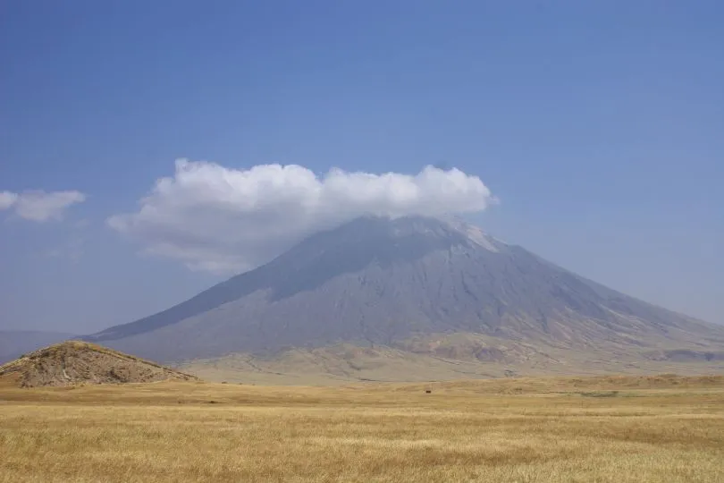 Ein Vulkan in Tansania thront über einer kargen Steppenlandschaft.