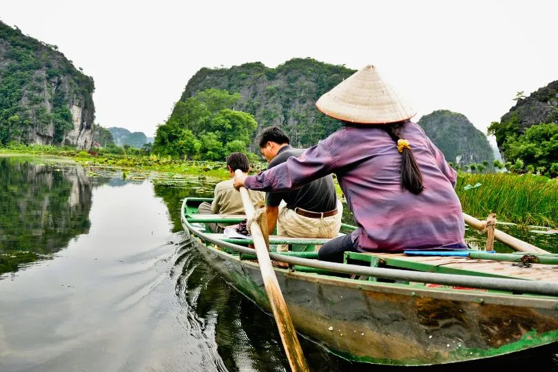 Einheimische fahren in einem Kanu durch einen ruhigen Fluss im Vietnam. 