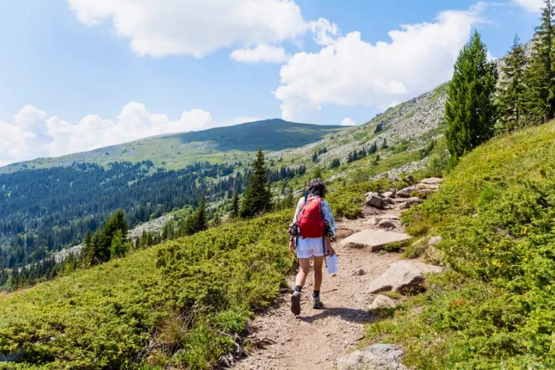 Frau wandert auf einem schmalen Pfad in Bulgariens Bergen im Sommer.