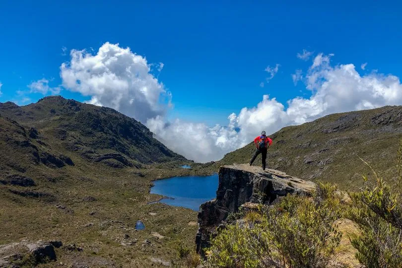 Wanderer steht auf einem Felsen am Cerro Chirripo in Costa Rica und schaut auf einen Bergsee hinab.