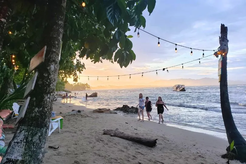 Touristen laufen über den Strand Puerto Viejo in Costa Rica. Er ist mit einer Girlande beschmückt.