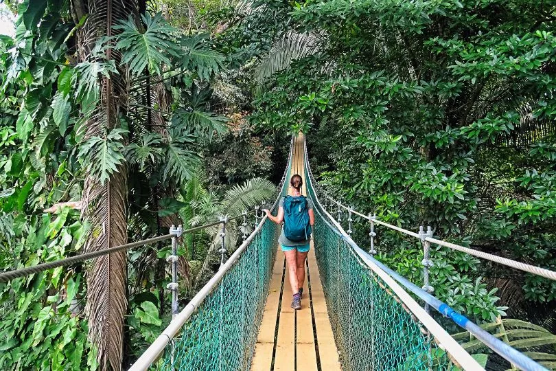 Reisende läuft über eine Hängebrücke im tiefen Dschungel Costa Ricas.