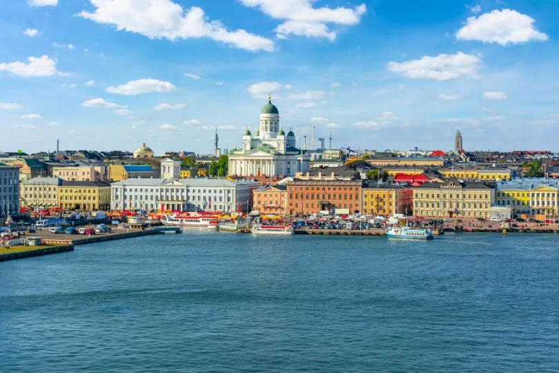 Aussicht auf die finnische Hauptstadt Helsinki mit ihren bunten Gebäuden, der weißen Kirche und dem Wasser am Hafen.