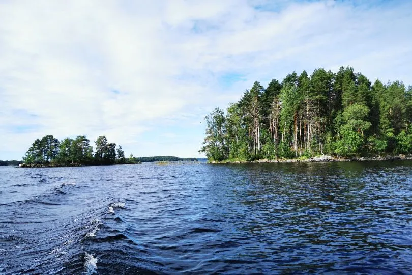 Dunkelblaues Wasser vor einer kleinen Insel voller grüner Tannen im Linansaari Nationalpark in Finnland.