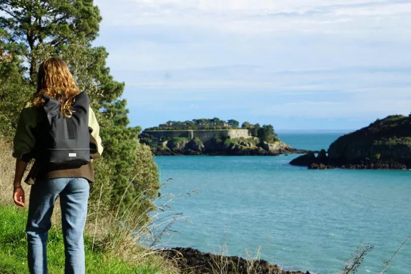 Frau wandert auf einem grünen Pfad entlang des Meeres in der Bretagne, Frankreich.