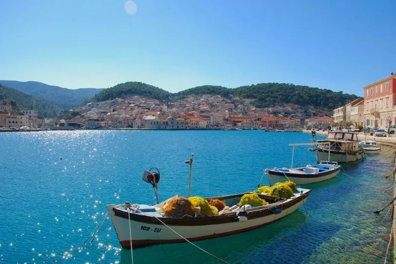 Kleine Fischerboote stehen im türkisen Wasser eines Hafens in Kroatien.