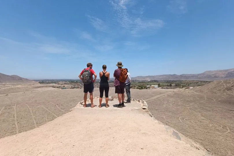 Touristen stehen auf einem Aussichtpunkt und schauen sich die Nazca Linien in Peru an.