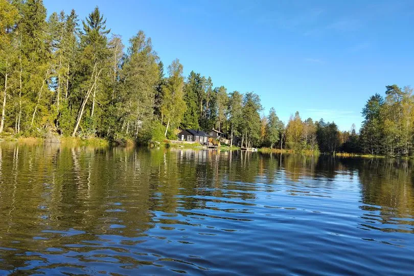 Nadelbäume spiegeln sich in einem klaren See in Schweden bei einer Kanutour.