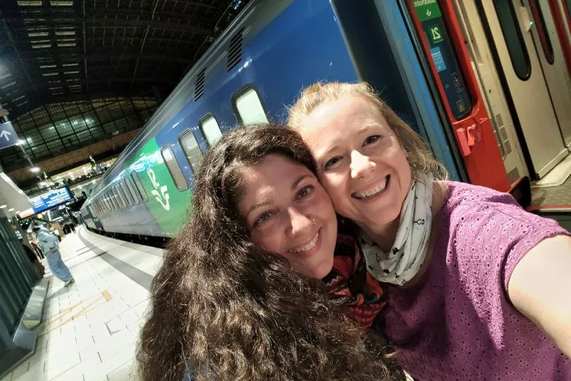 Zwei Frauen stehen am Bahngleis vor einem Nachtzug in Hamburg und machen ein Selfie.